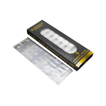 Une boîte rectangulaire noire et dorée étiquetée Sacs pour Machine Bishop Power Wand, avec une fenêtre transparente, à côté d'une pile de sacs en plastique transparents ornés de motifs de flocons de neige blancs.