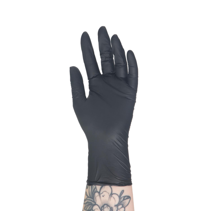 Une main tatouée portant un gant en nitrile noir Killer Beauty (boîte de 100 gants) est levée, paume vers l’extérieur, sur un fond blanc.