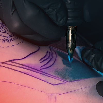 Un gros plan d’une personne recevant un ombrage bleu dans son tatouage.